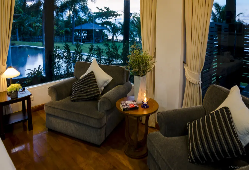 Nah Talay seating area with armchairs by the window, looking out at the pool and garden