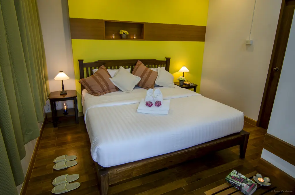 Ruam Mitr bedroom with double bed and yellow-green wall