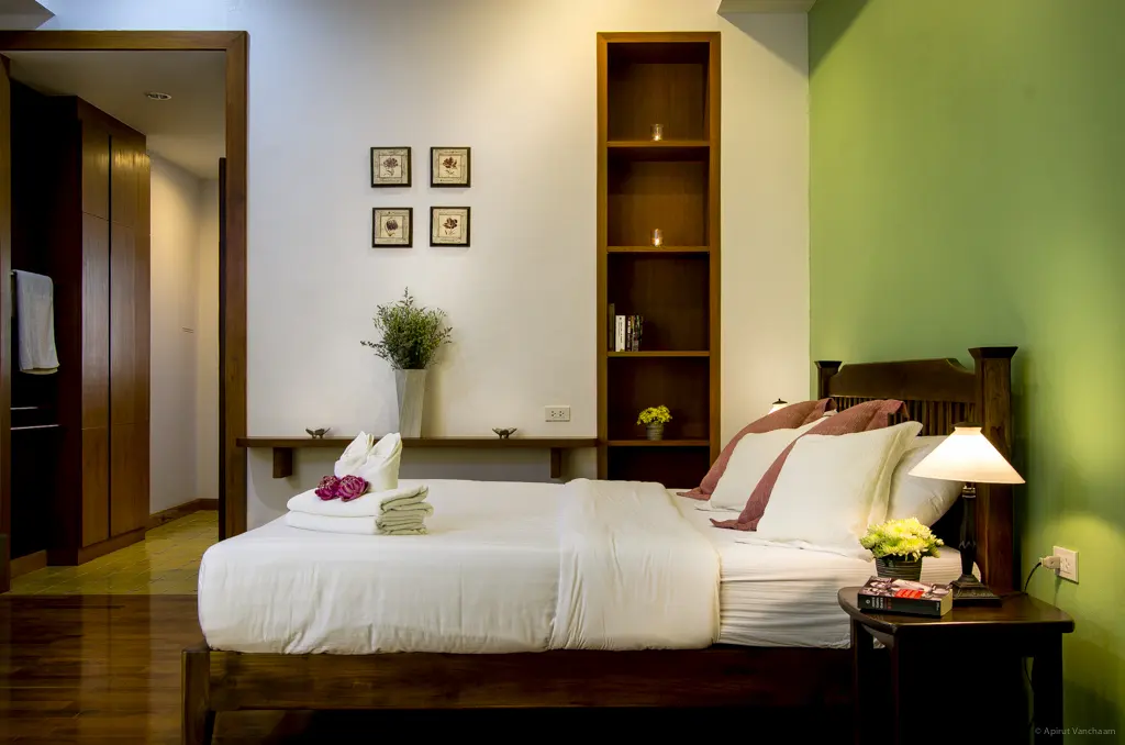 Chom Suan bedroom with double bed, shelves and green wall