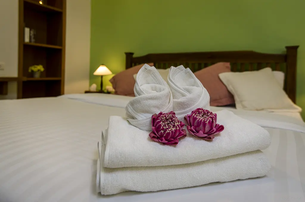 Folded towels and flowers on a made bed