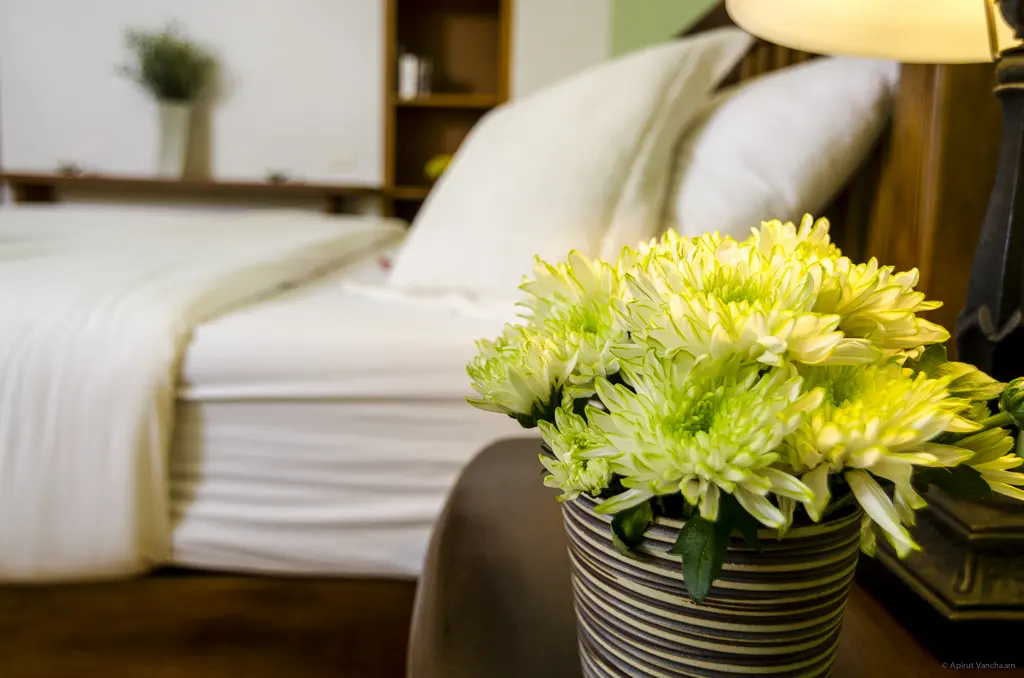 Close-up of pillows and yellow flowers on a bedside table