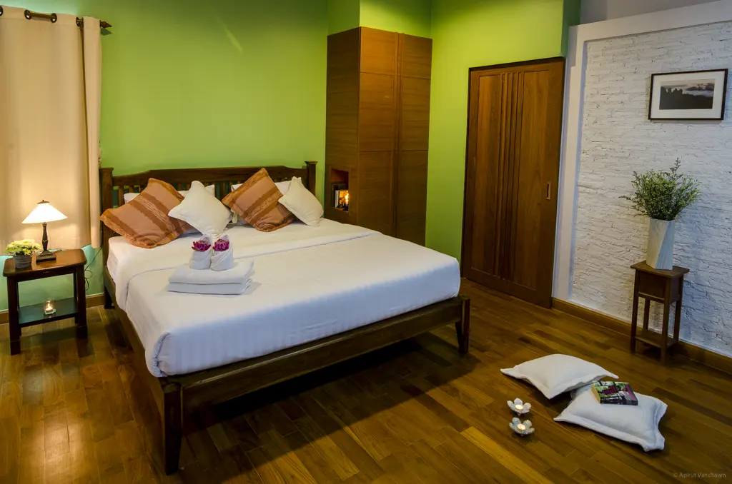 Ruam Mitr bedroom with double bed, wardrobe and green wall